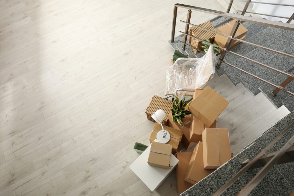 A cluttered staircase with scattered boxes, packaging materials, and a broken lamp, reflecting a mess likely due to moving or unpacking and in need of residential cleaning in Baton Rouge.